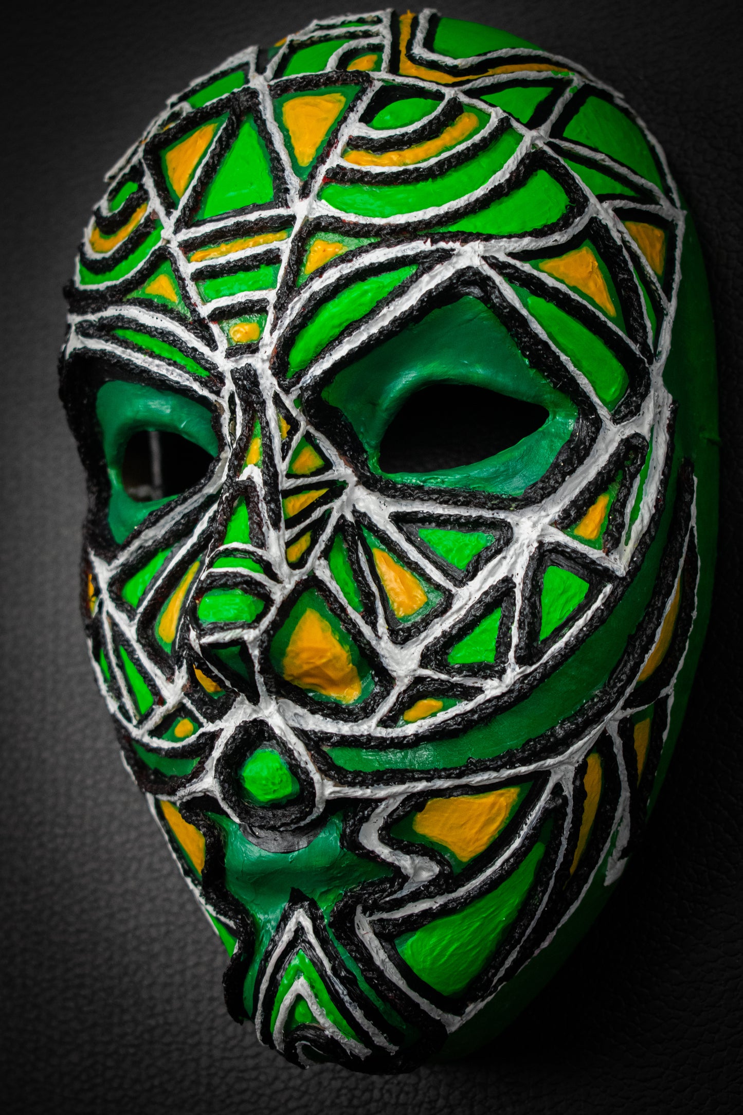 Masque artisanal vert avec motifs peints Ă la main.