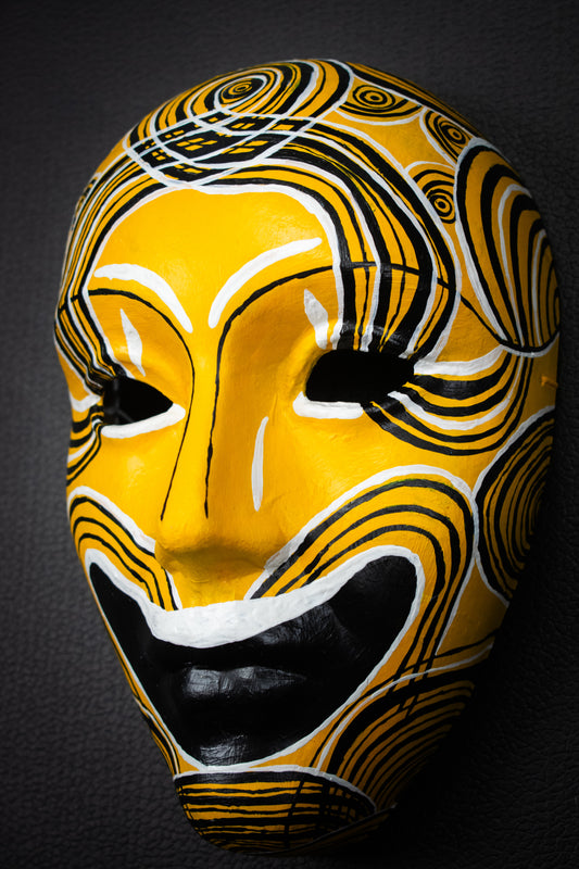 Masque artisanal jaune avec motifs noir peints à la main.