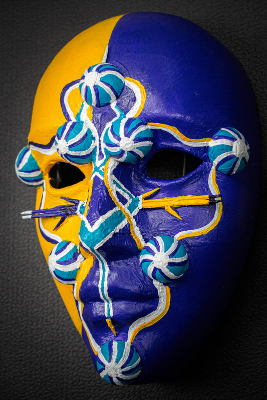 Masque artisanal jaune et violet avec motifs peints à la main.