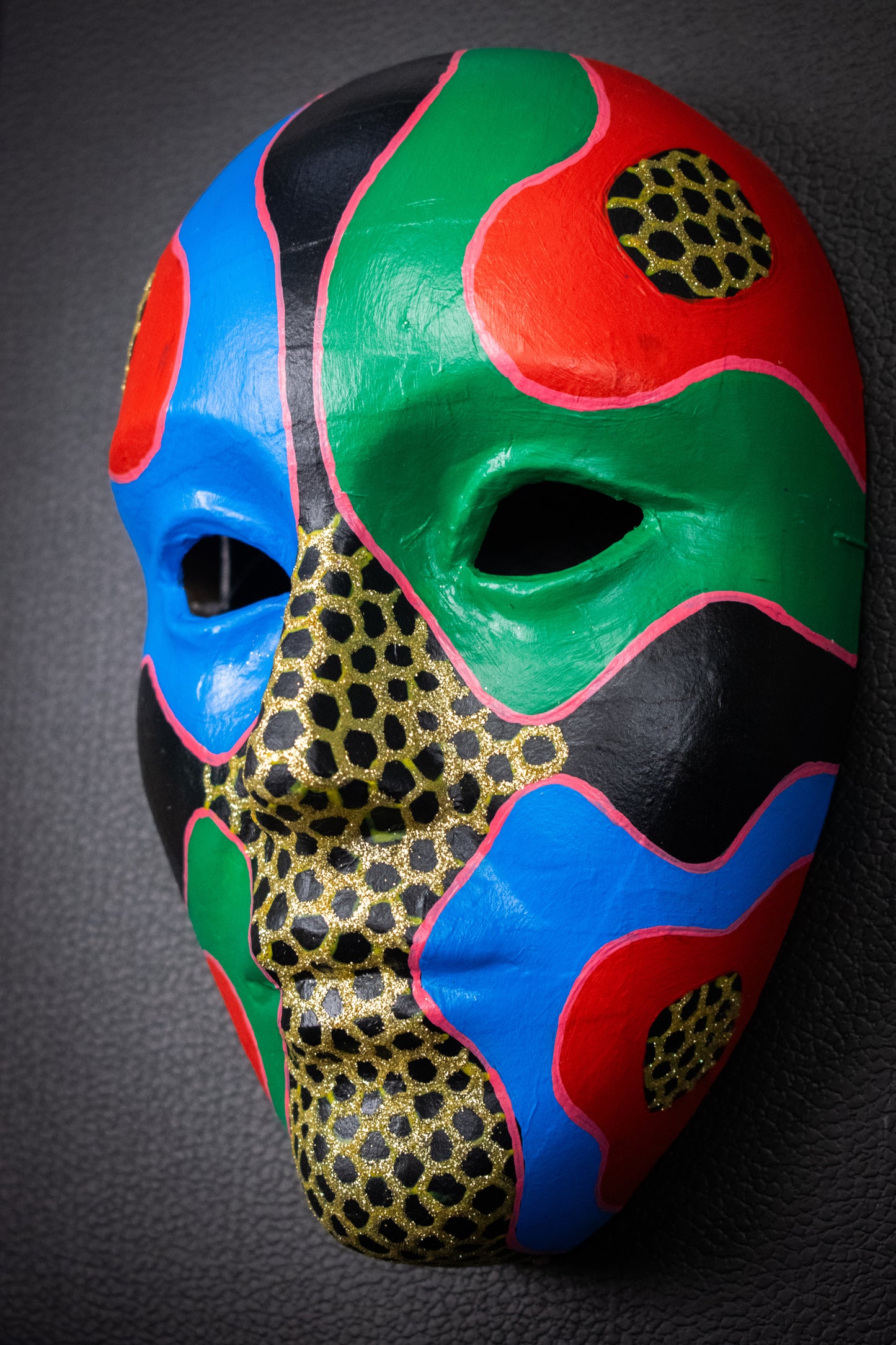 Masque artisanal rouge, bleu, vert avec motifs peints à la main.