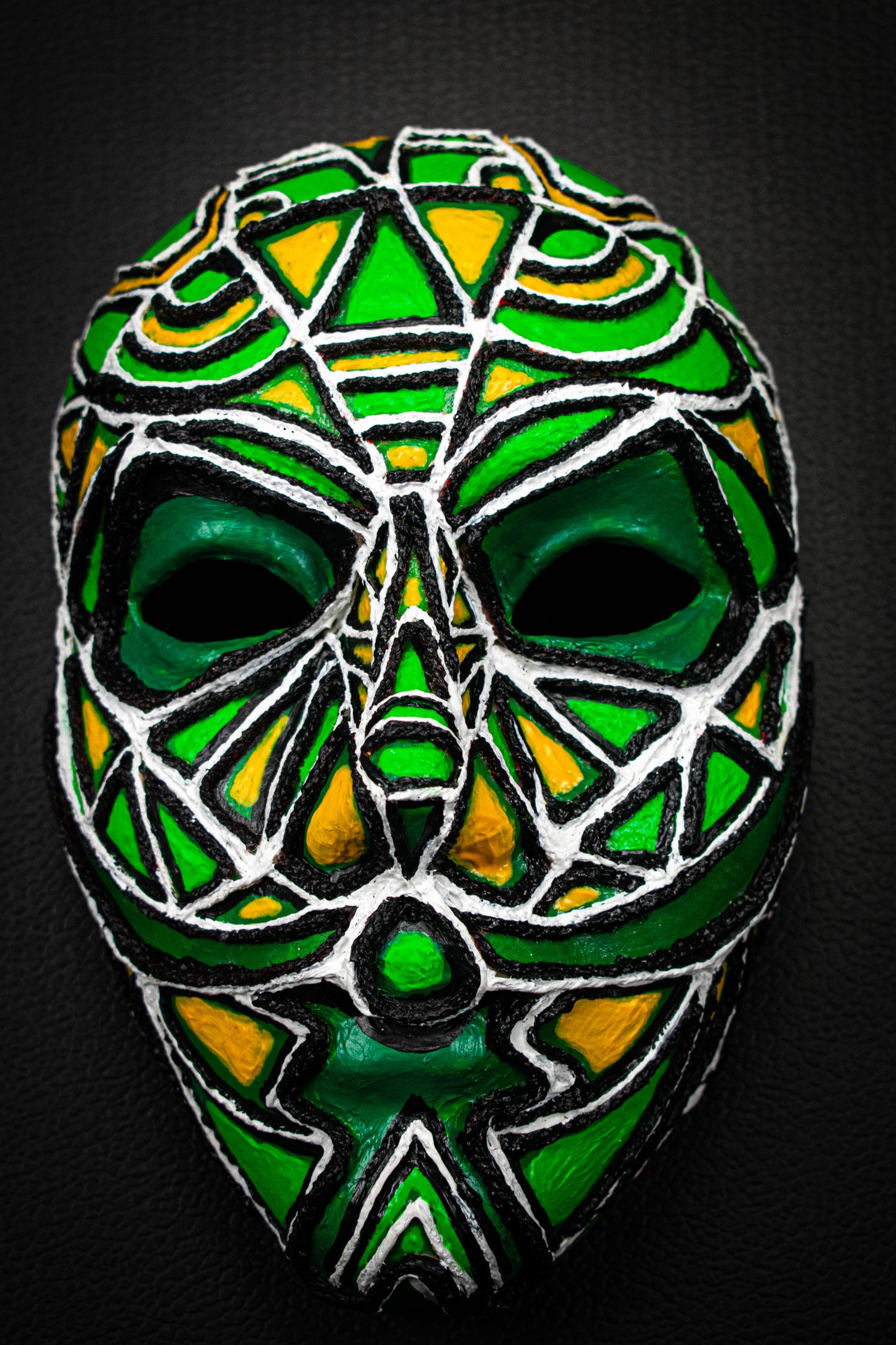 Masque artisanal vert avec motifs peints à la main.