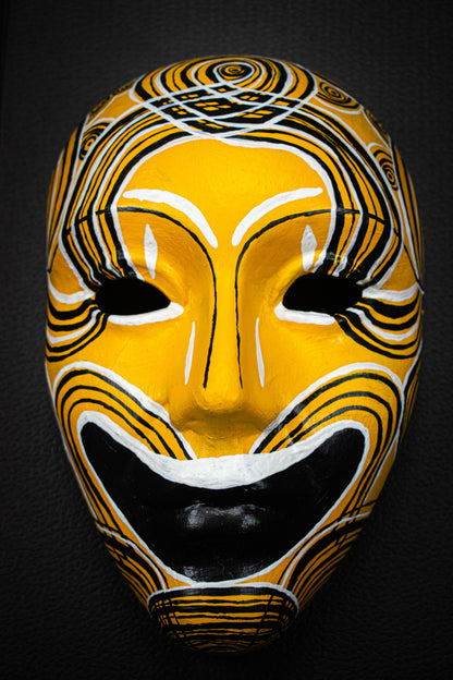 Masque artisanal jaune avec motifs noir peints à la main.