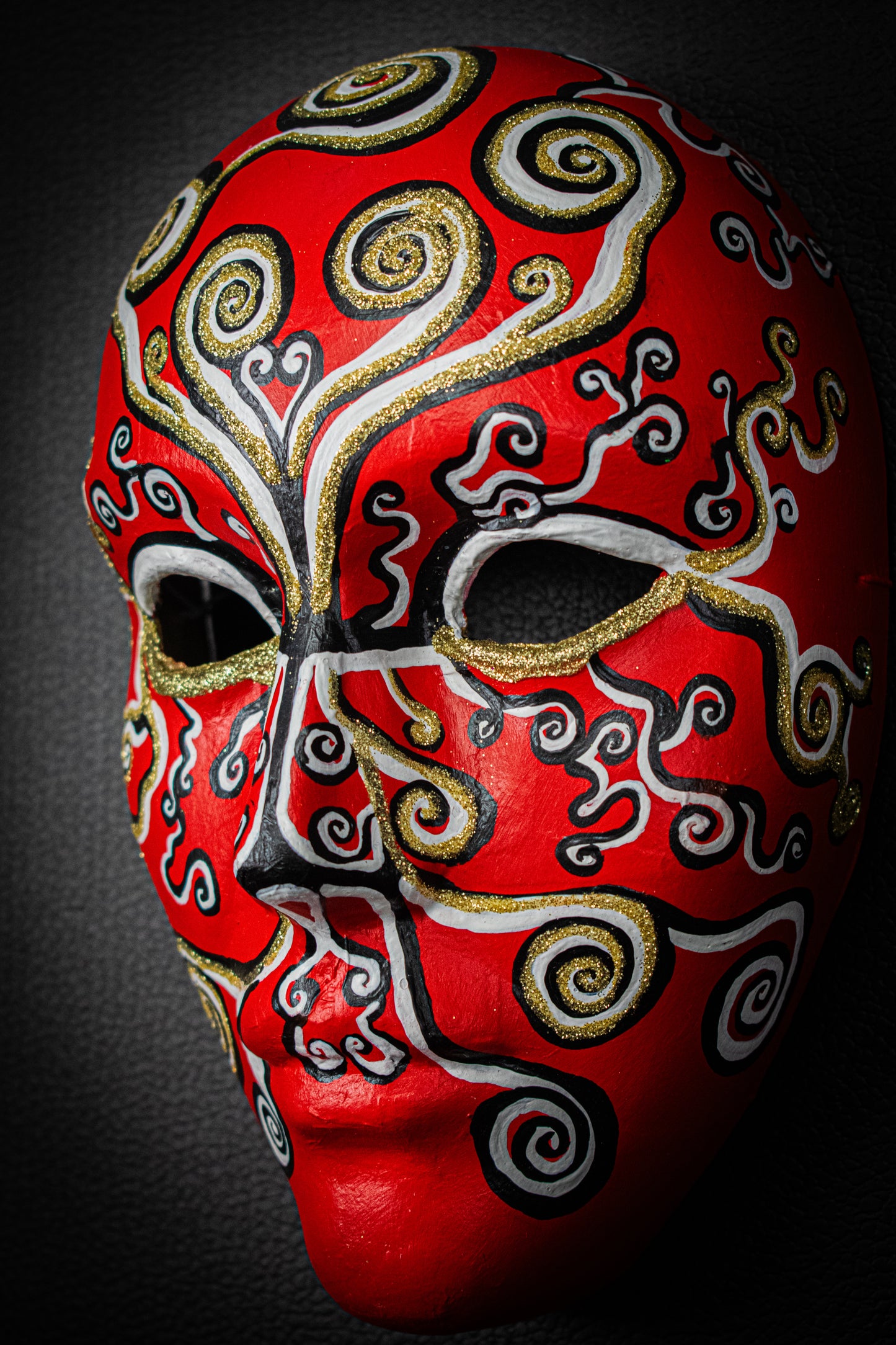 Masque artisanal rouge avec motifs peints à la main. 