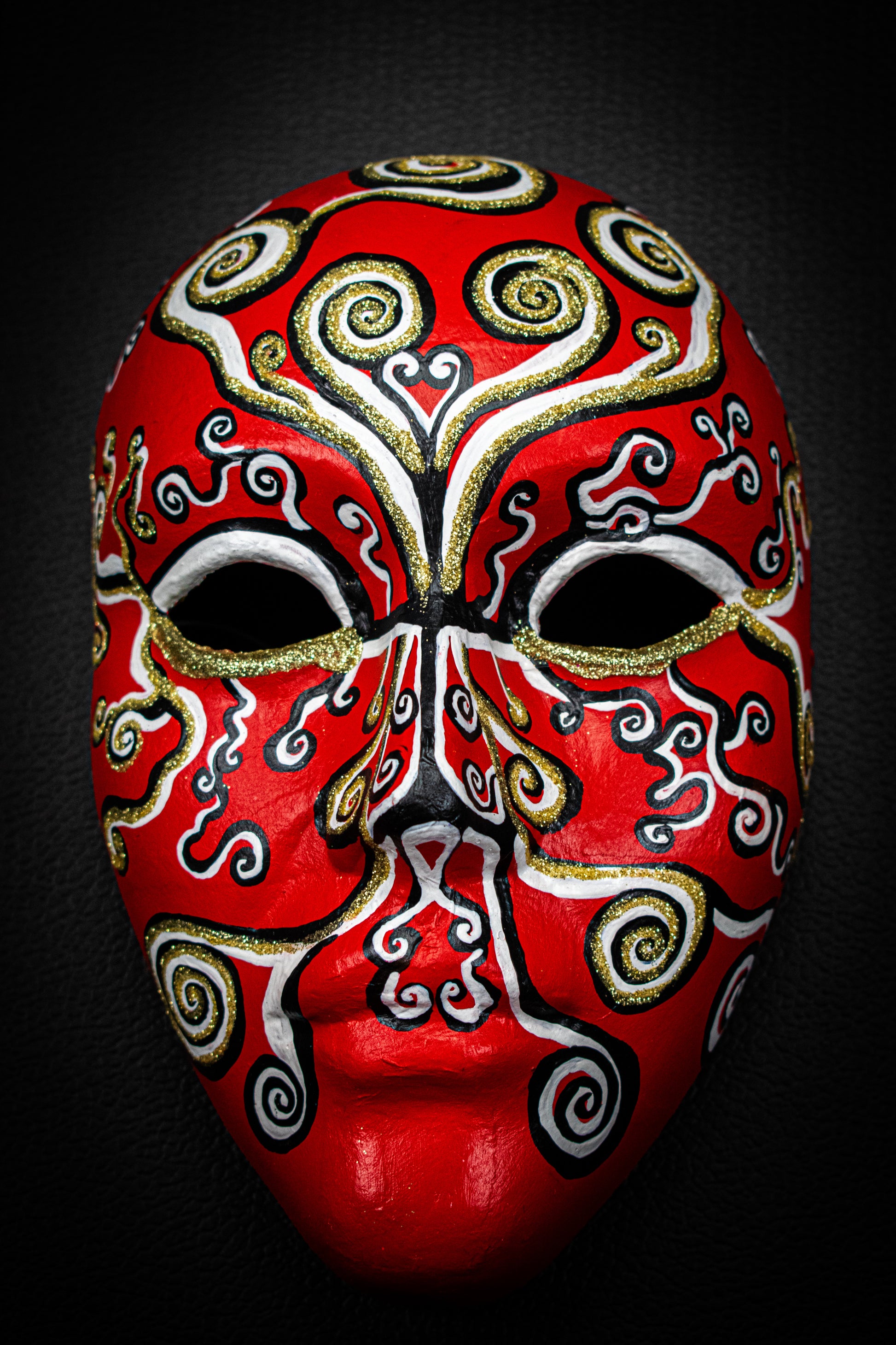 Masque artisanal rouge avec motifs peints à la main.