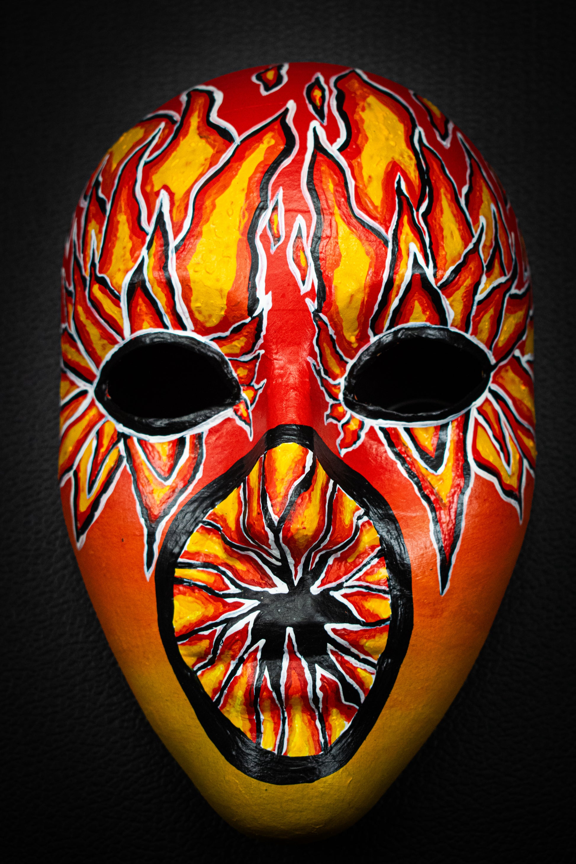 Masque artisanal orange avec motifs noir peints à la main.