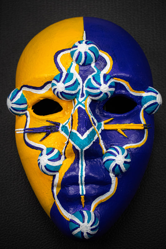 Masque artisanal jaune et violet avec motifs noir peints à la main.